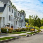 neighborhood street with white homes raised porches and fall plantings