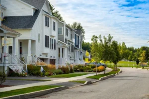 neighborhood street with white homes raised porches and fall plantings