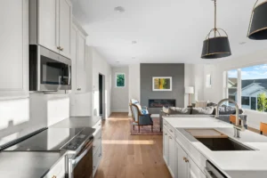 open kitchen with white cabinets stainless appliances and living room fireplace view