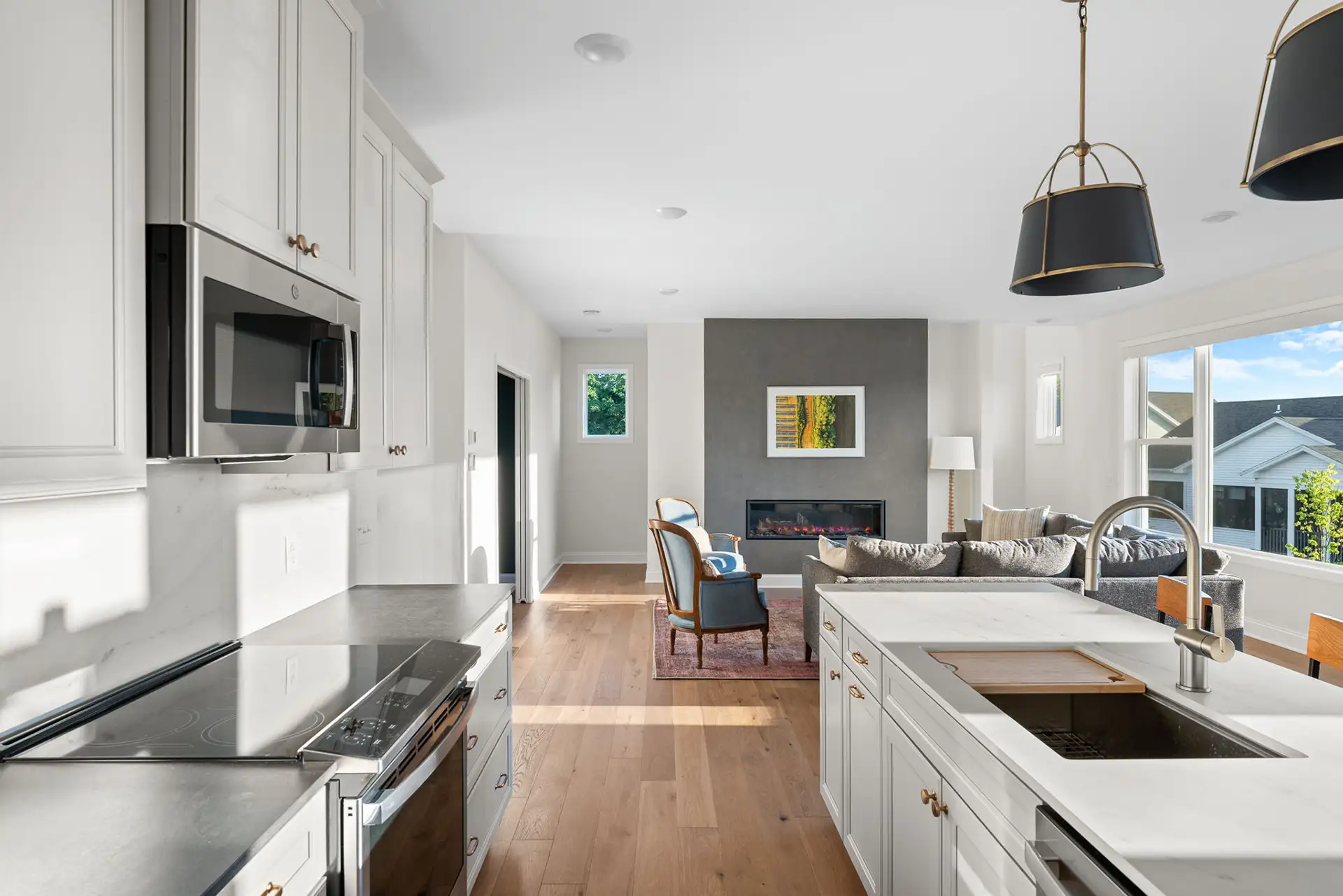 open kitchen with white cabinets stainless appliances and living room fireplace view