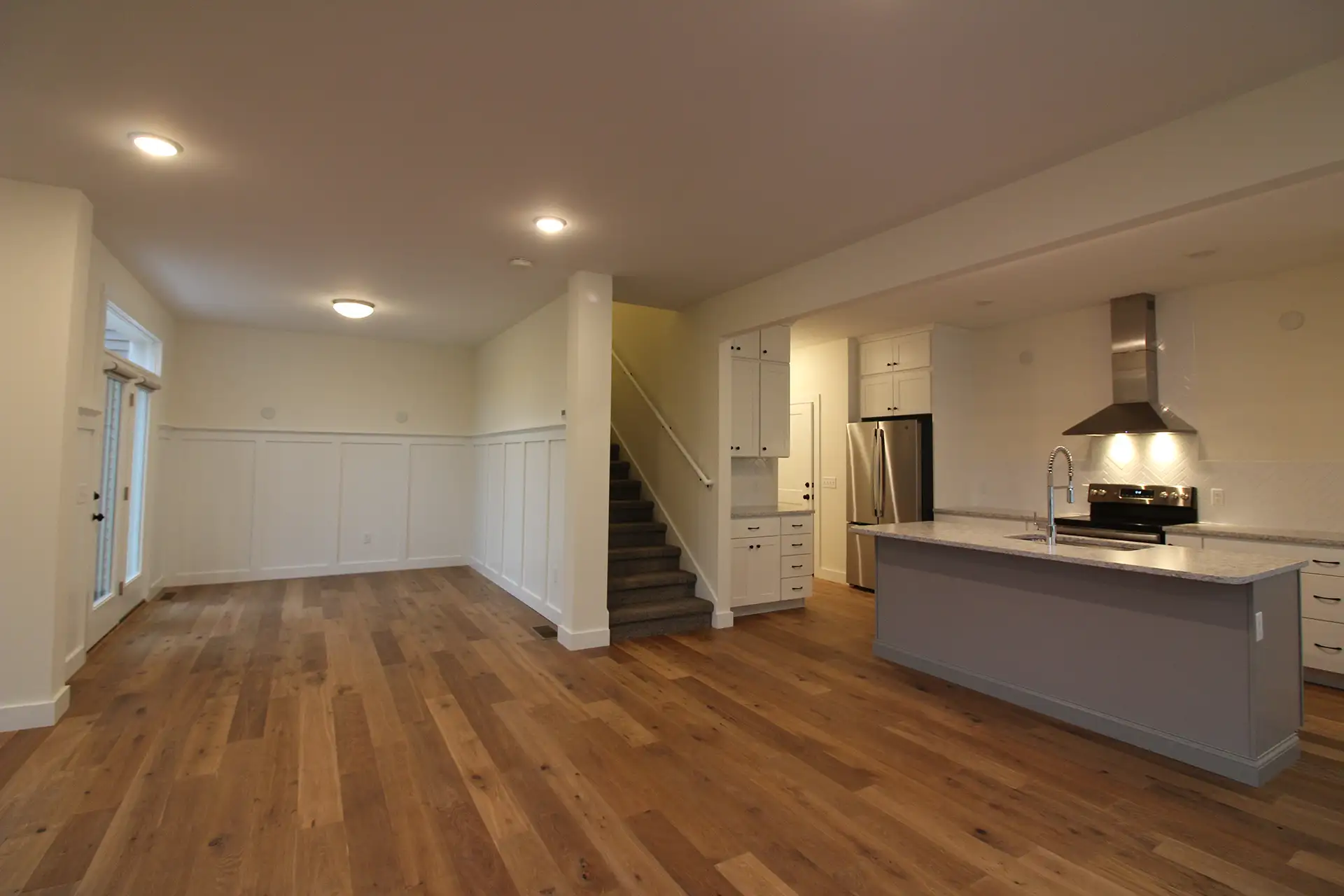 open plan wainscoting wall gray island staircase kitchen