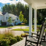 porch with black rocking chairs overlooking tree lined neighborhood street
