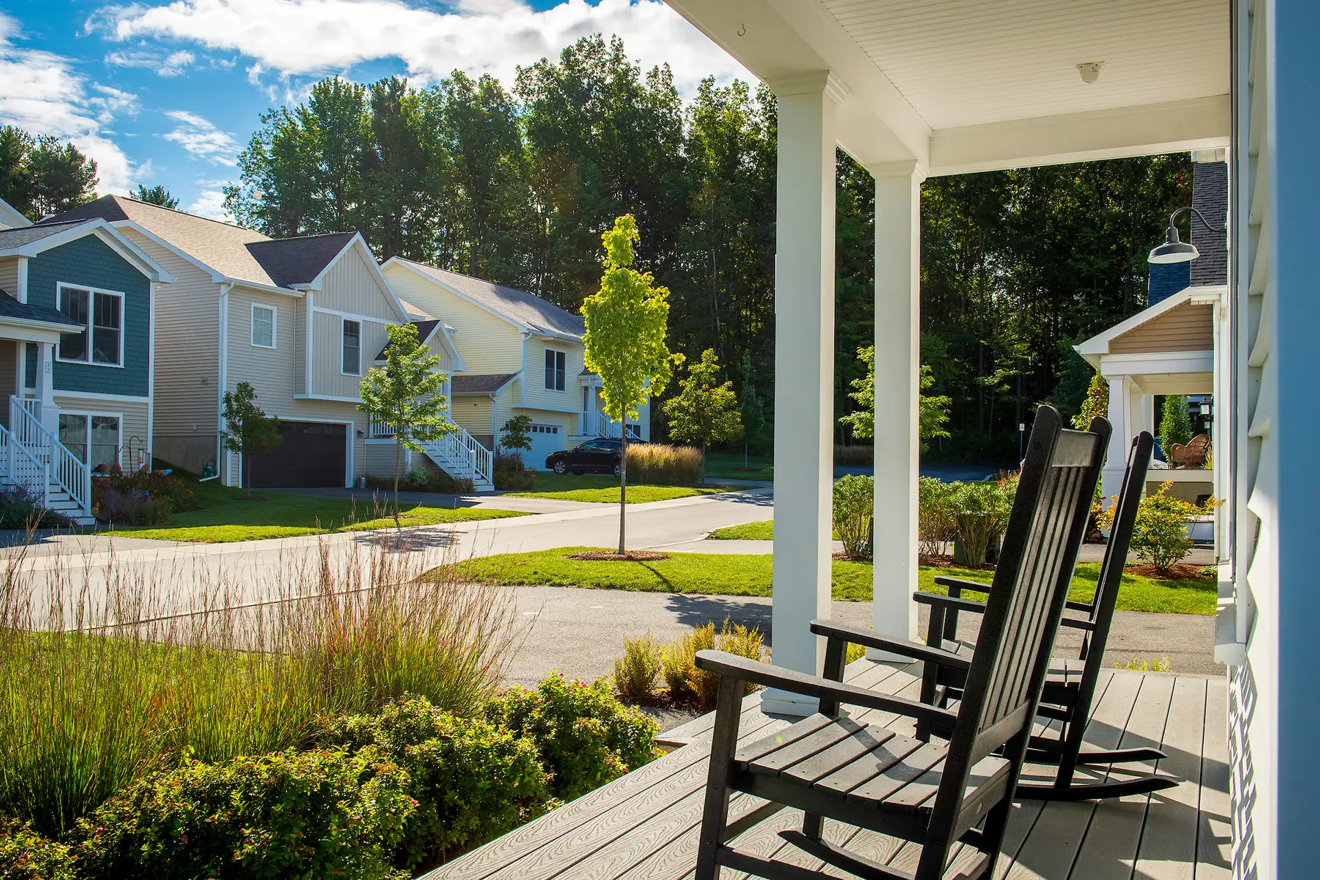 porch with black rocking chairs overlooking tree lined neighborhood street