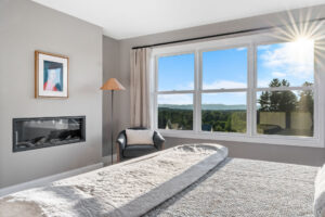 primary bedroom with linear fireplace and mountain view window