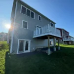 rear exterior with elevated deck french doors and green lawn