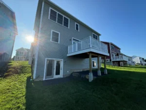 rear exterior with elevated deck french doors and green lawn