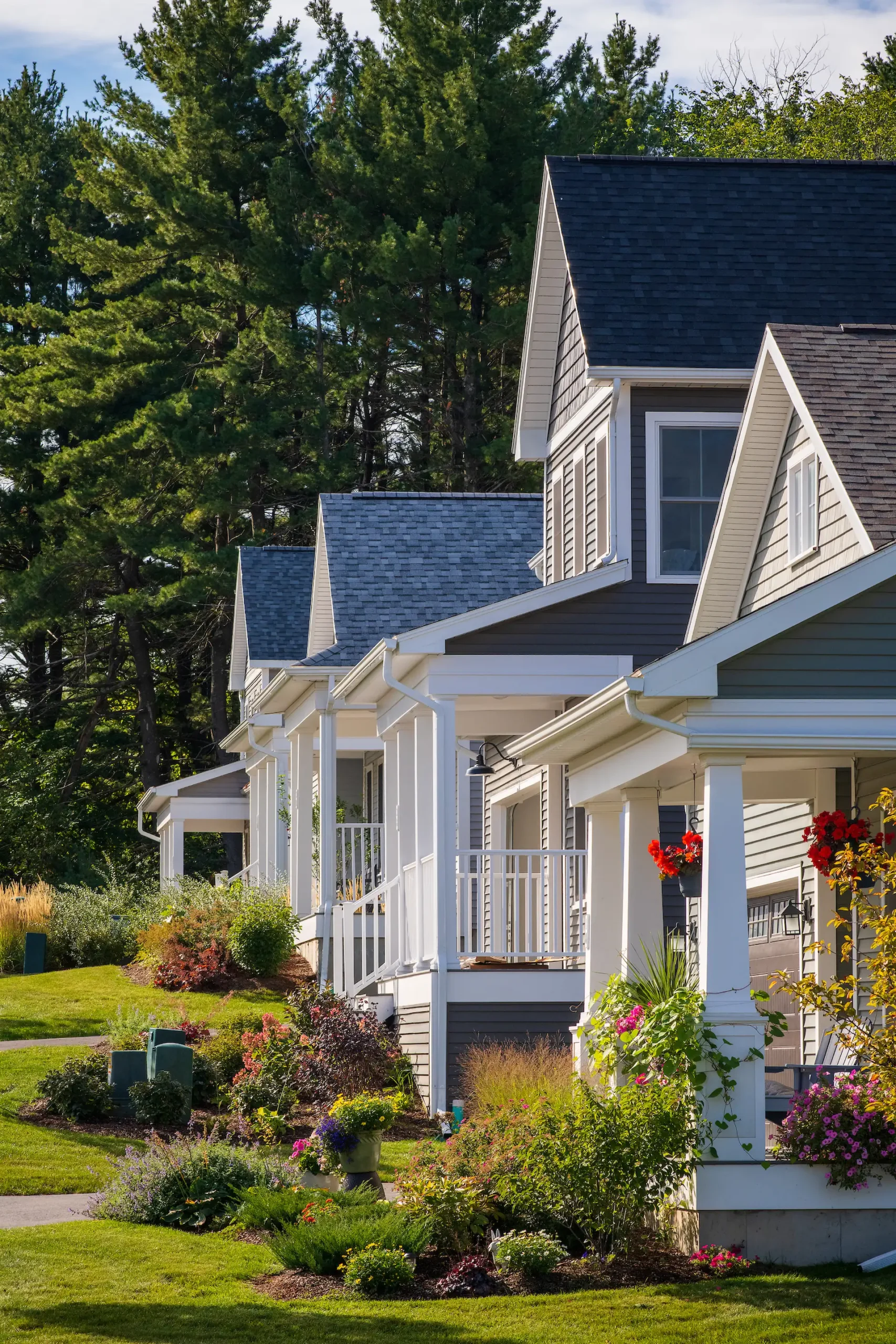 row of craftsman homes with covered porches and flower gardens