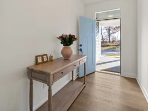staged foyer blue front door wood console table flower vase