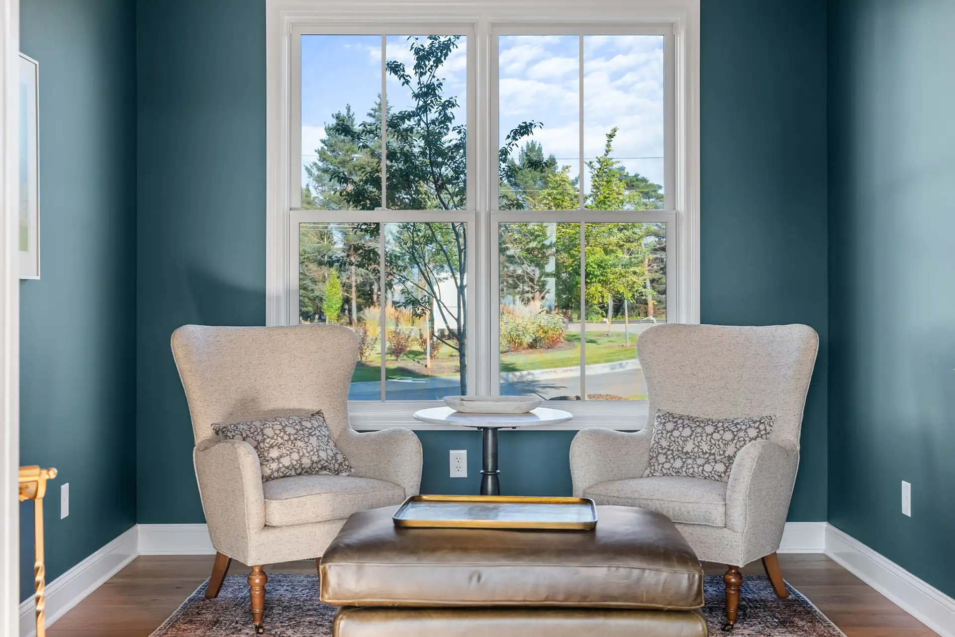 teal sitting room with two wingback chairs and garden view window