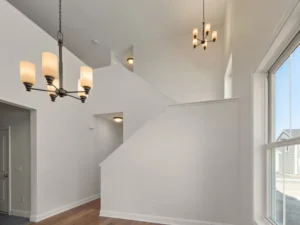 two story foyer staircase with double chandelier and tall windows
