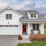 white home exterior with red adirondack chairs and ornamental grasses