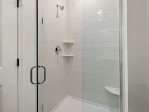 white glass enclosed shower with corner shelf and marble bench