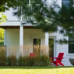 white farmhouse exterior with red door black rockers and garage