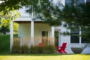 white farmhouse exterior with red door black rockers and garage