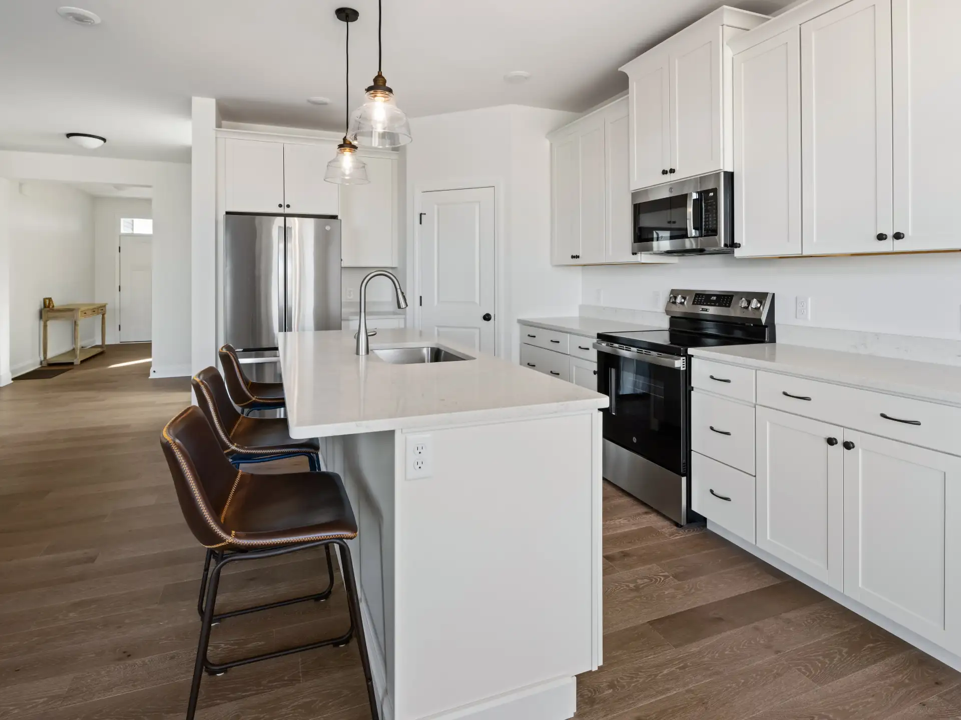 white kitchen leather barstools glass pendants hallway view