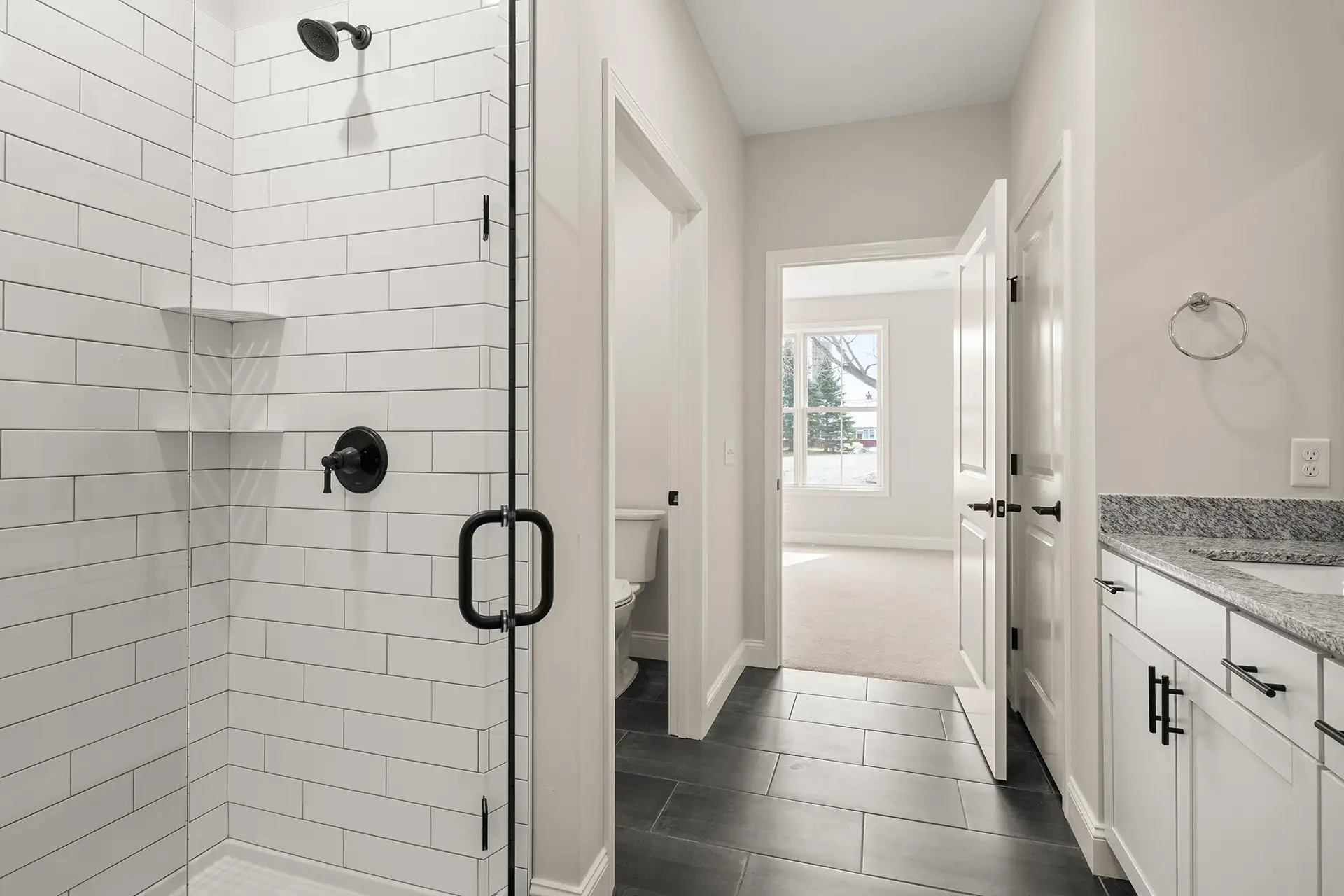 white subway tile shower with black fixtures and granite vanity